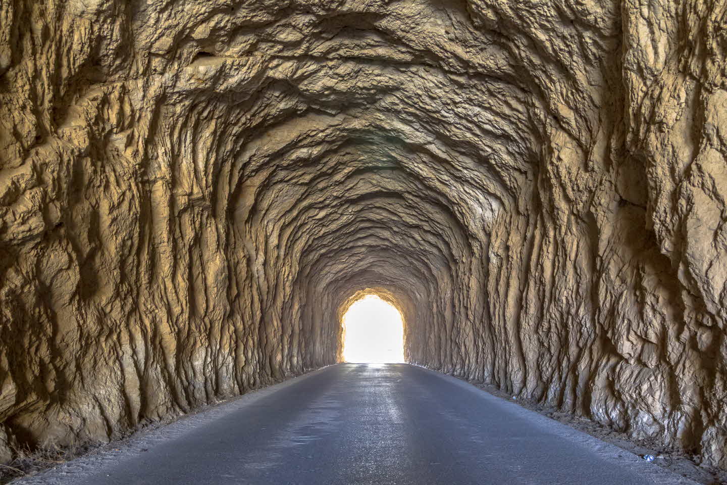 Bright light at the end of the tunnel. Ancient tunnel with rough walls.